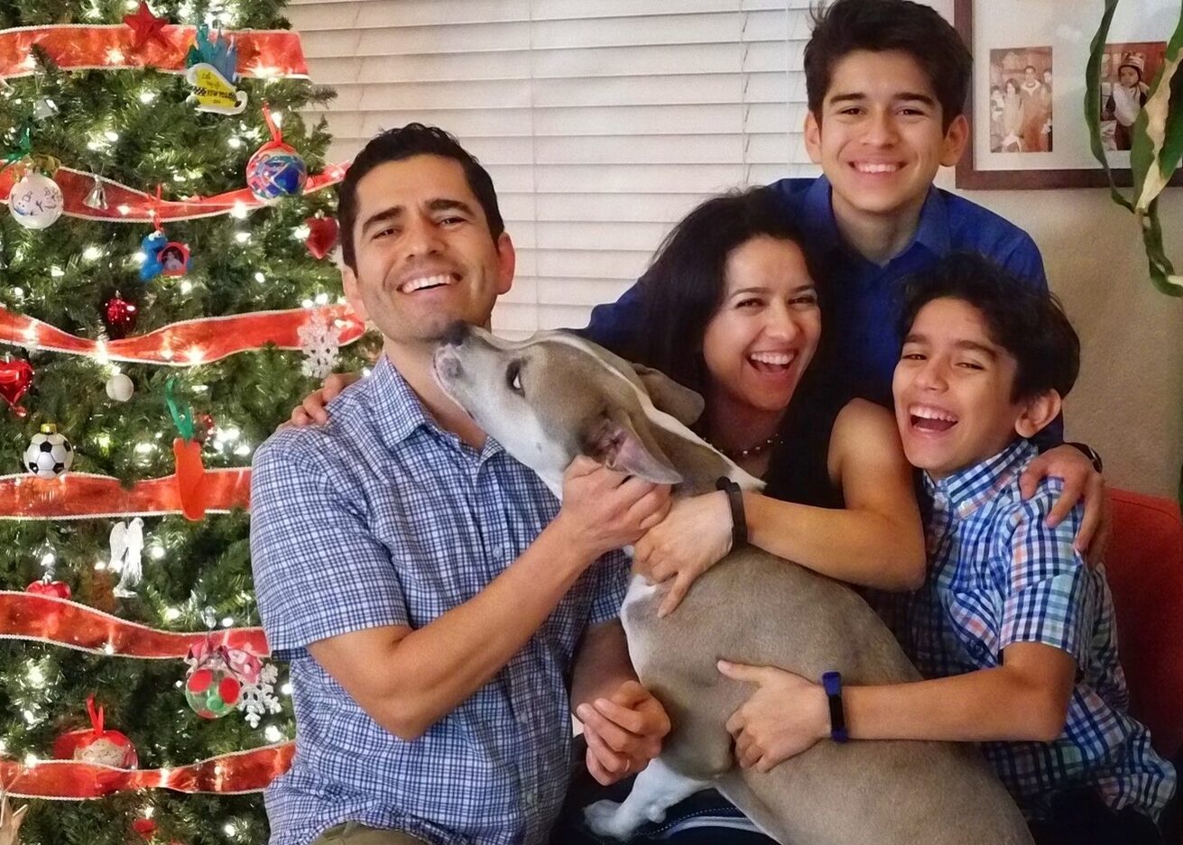 a family and dog in front of a Christmas tree
